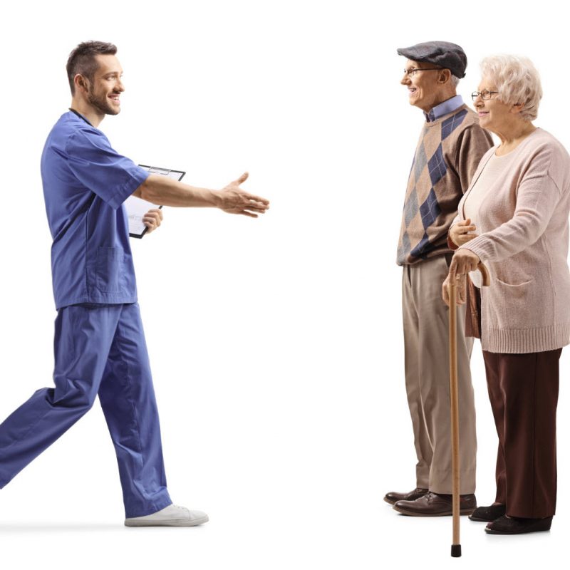 male-health-worker-walking-and-greeting-elderly-patients-with-hand